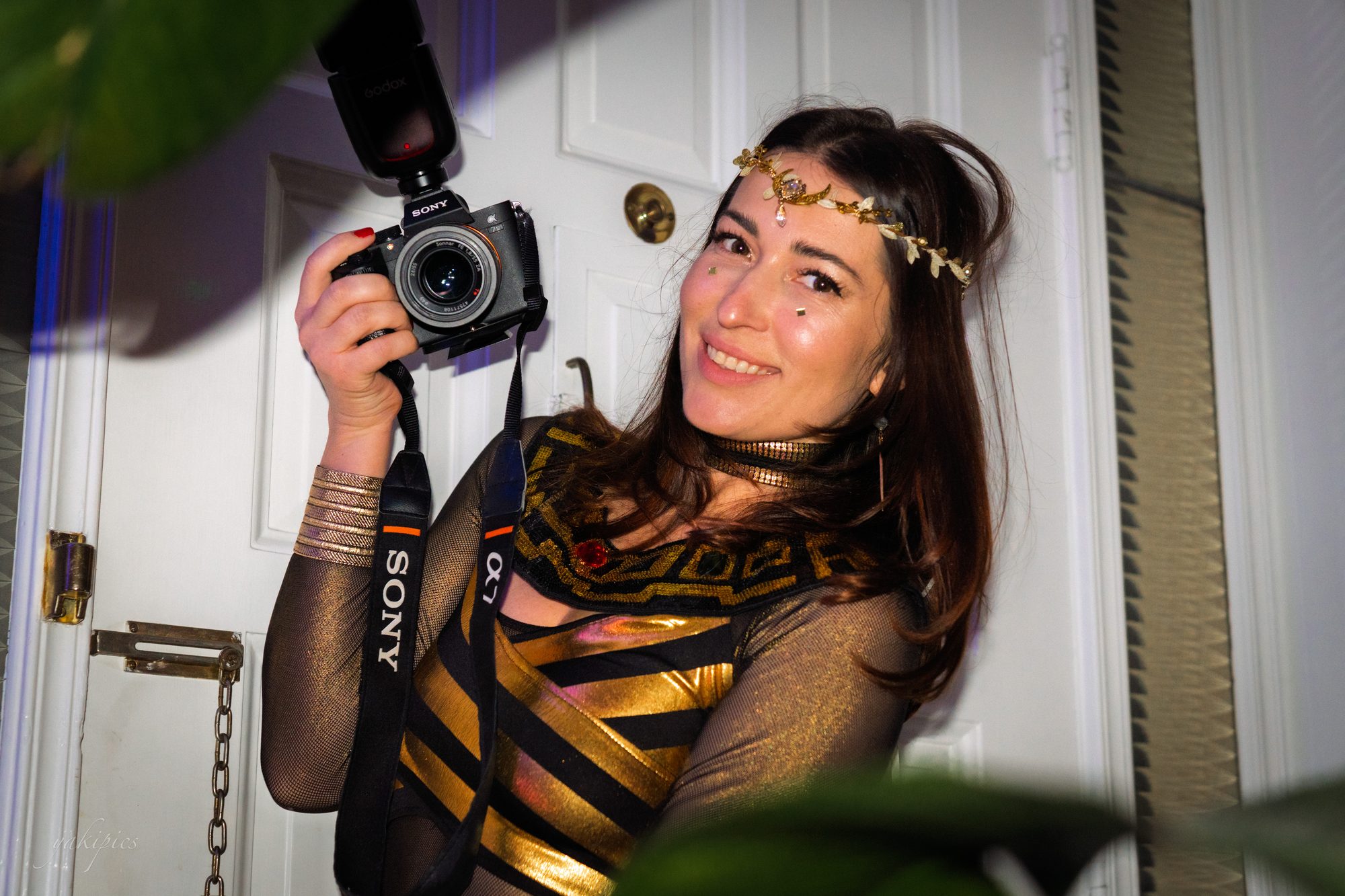 Woman holding a camera and smiling from inside a lively party.