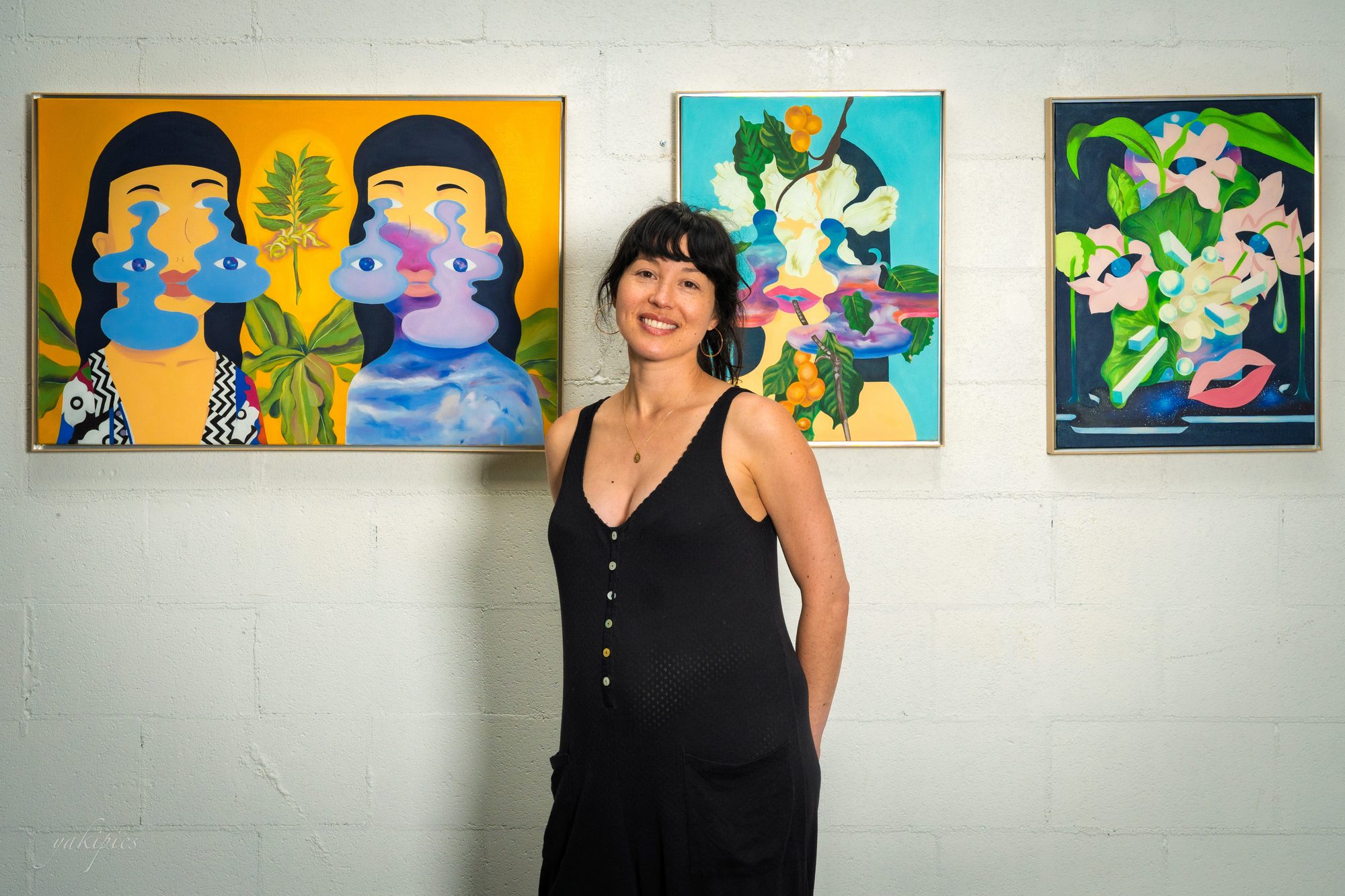 Artist standing with a series of vivid figurative paintings.