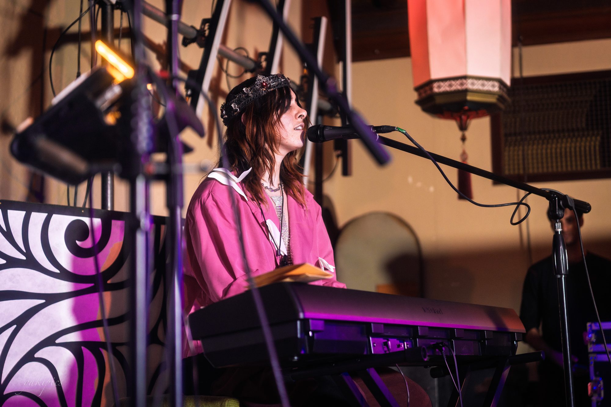 Keyboardist singing beneath stage lights.