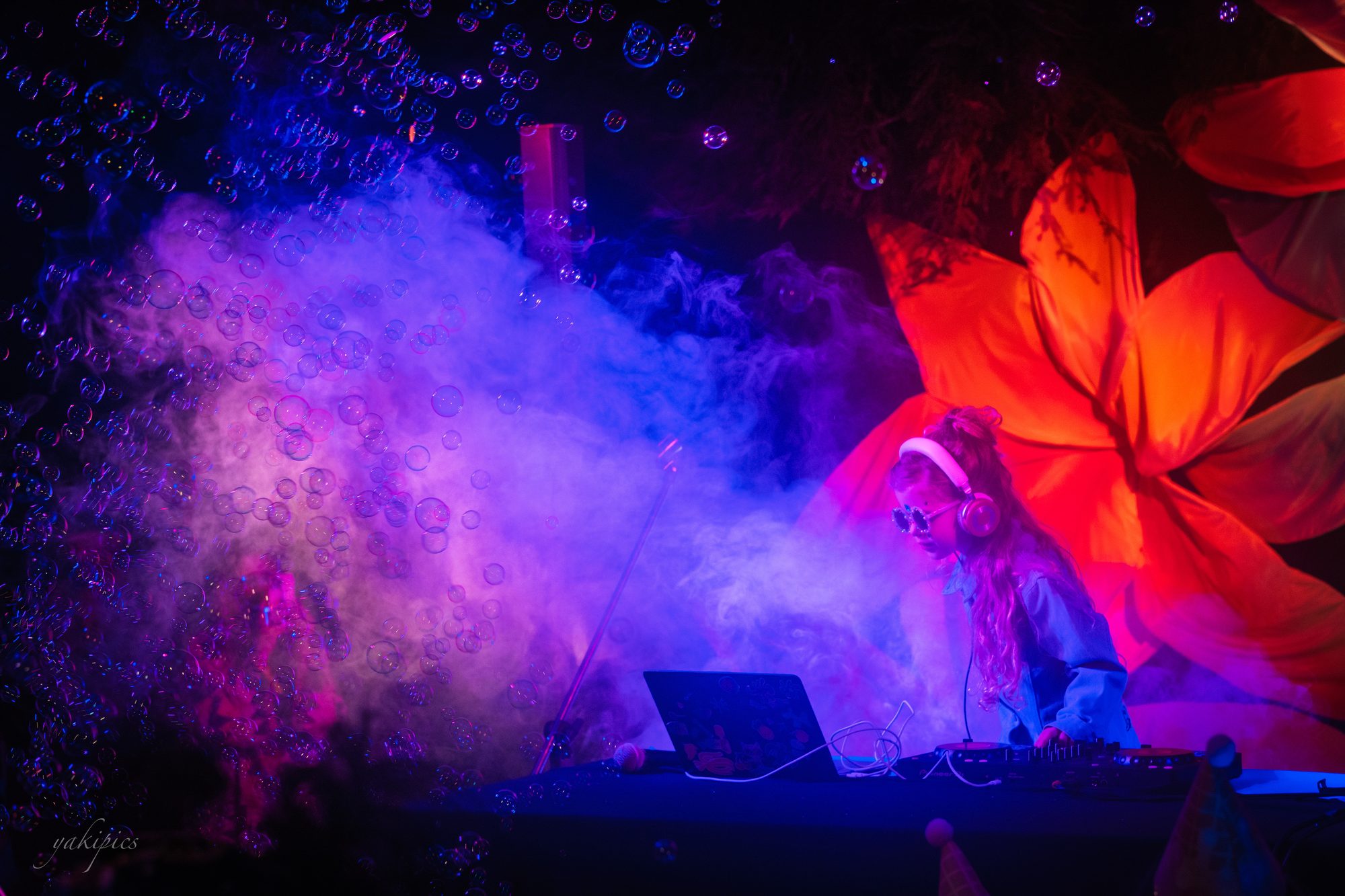 Performer partially obscured by violet smoke and saturated stage light.
