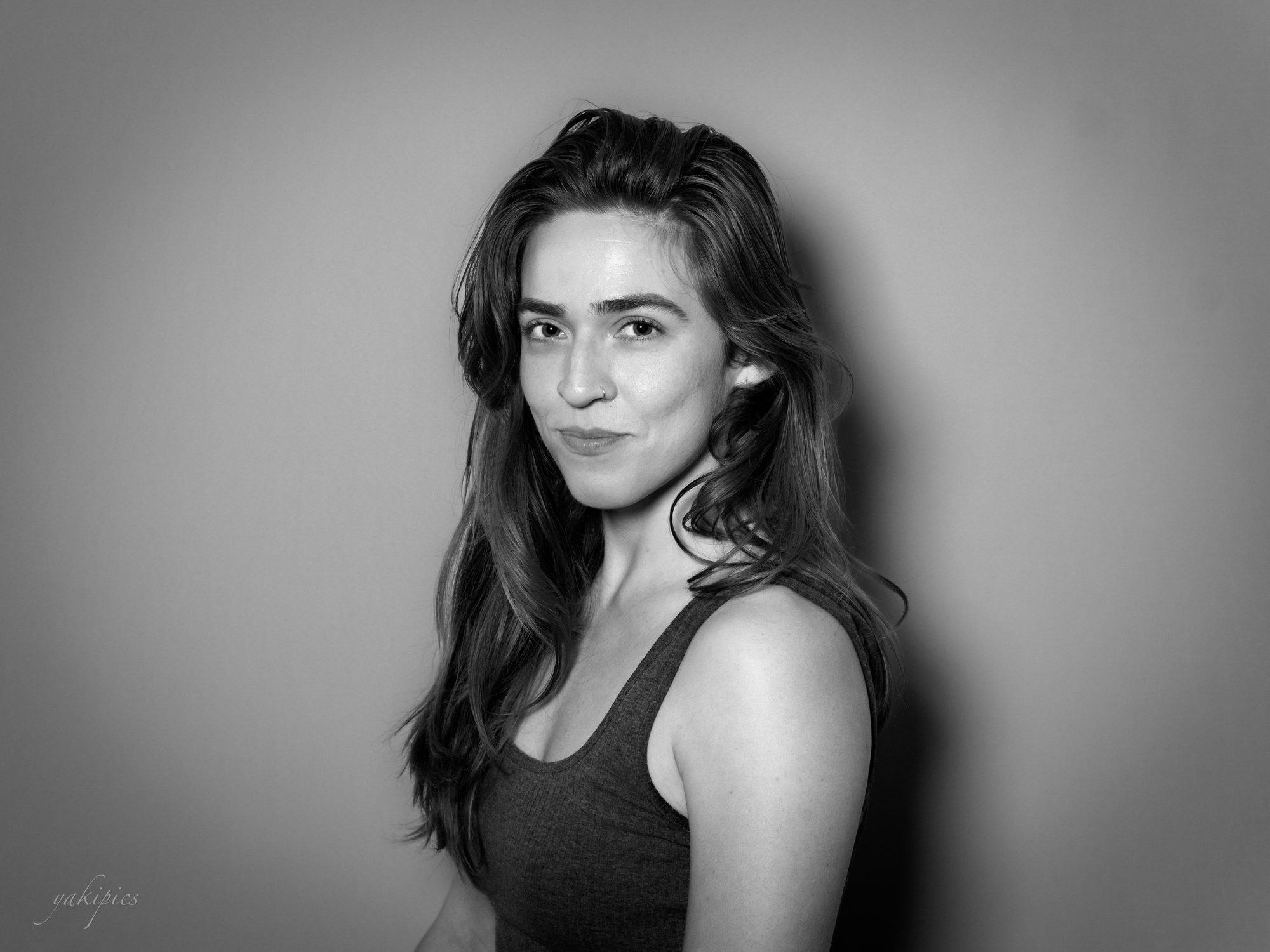 Black-and-white studio portrait of a woman with long hair turned toward the camera.