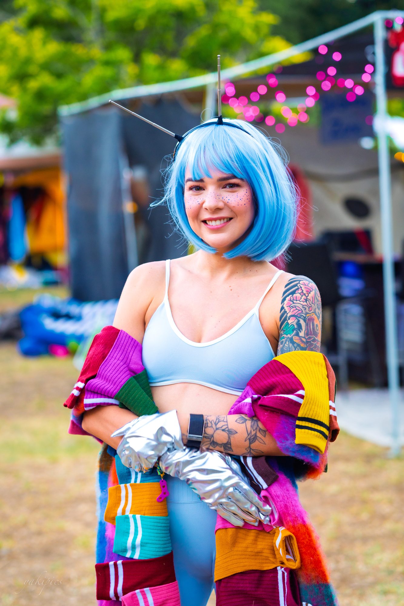 Woman with a blue wig and colorful costume looking directly at the camera.