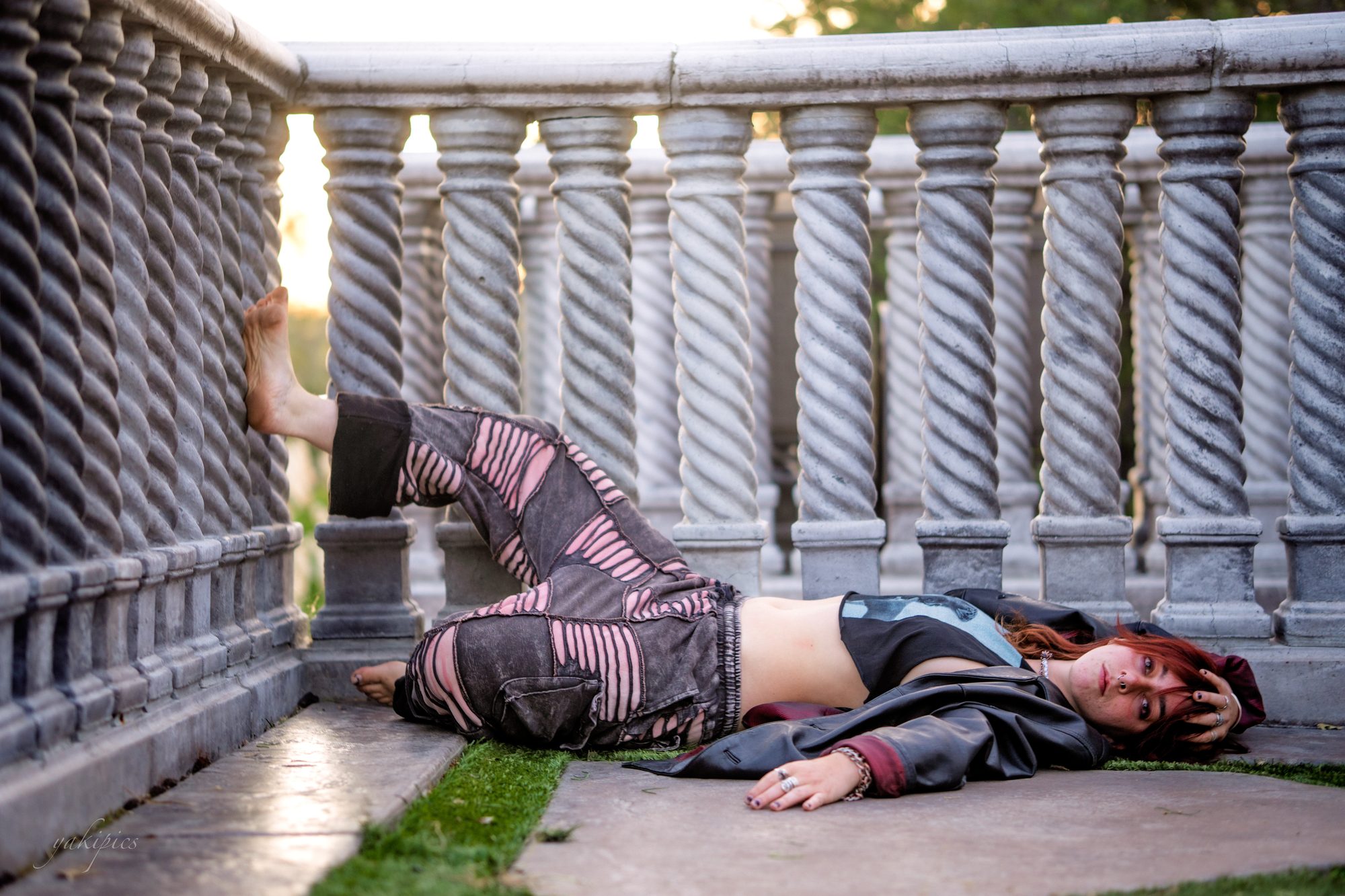 Woman reclining beside a stone balustrade in an unconventional environmental portrait.